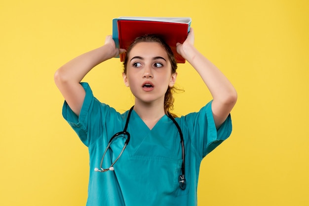 Widok z przodu kobieta lekarz w koszuli medycznej z notatkami, kolorowym wirusem emocji zdrowia covid-19 pandemiczny mundur