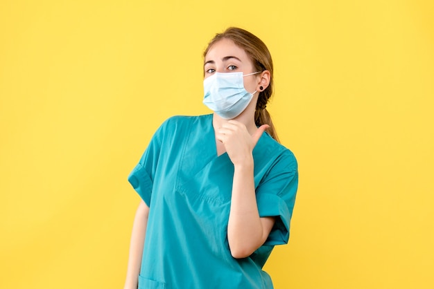 Widok z przodu kobieta lekarz w masce na żółtym biurku szpital zdrowia pandemiczny covid