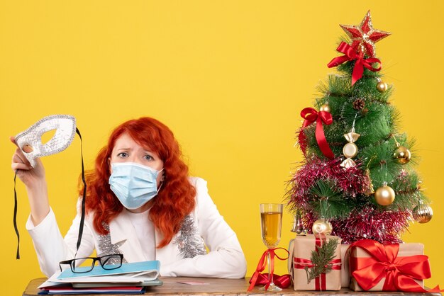 Widok z przodu kobieta lekarz w sterylnej masce trzyma maskę wokół świątecznych prezentów