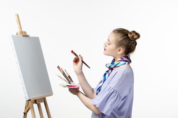 Widok z przodu kobieta malarz przygotowująca się do rysowania na białej ścianie farba obraz artystyczny ołówek sztalugowy artysty