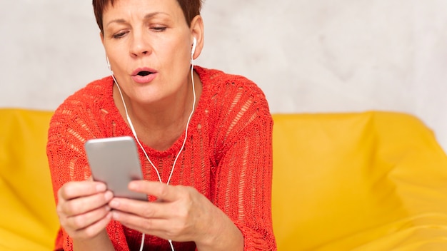 Bezpłatne zdjęcie widok z przodu kobieta słuchania muzyki i patrząc na telefon