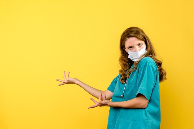 Widok z przodu kobiety lekarza w masce na żółtej ścianie