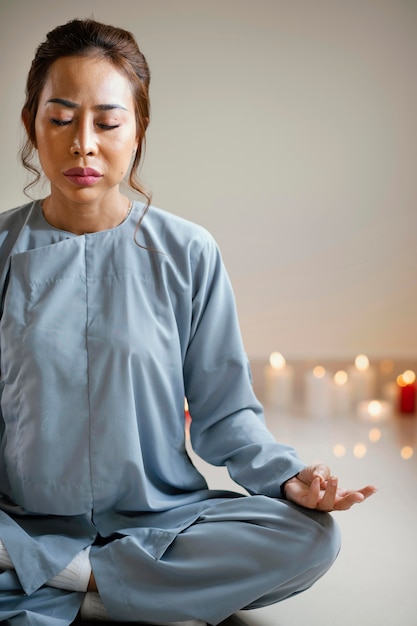 Bezpłatne zdjęcie widok z przodu kobiety medytacji obok świec z miejsca na kopię
