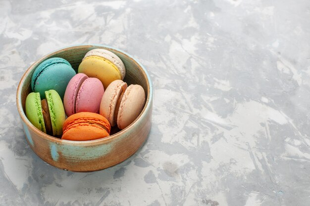 Widok z przodu kolorowe francuskie macarons pyszne ciasteczka na jasnobiałej powierzchni