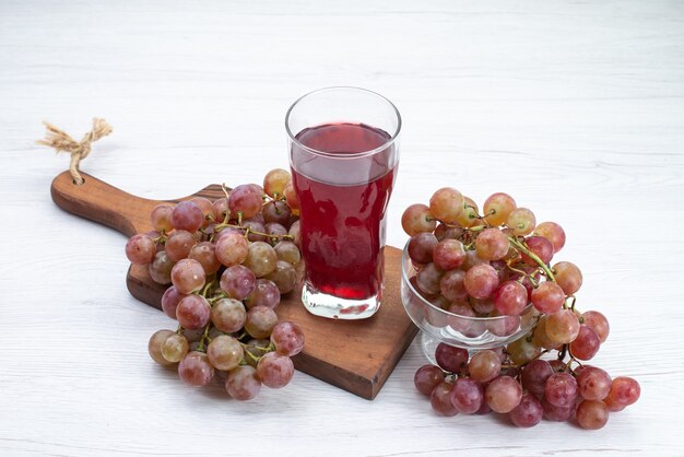 Widok z przodu kwaśne świeże winogrona z czerwonym sokiem na jasnym białym biurku owoc świeży łagodny napój sokowy
