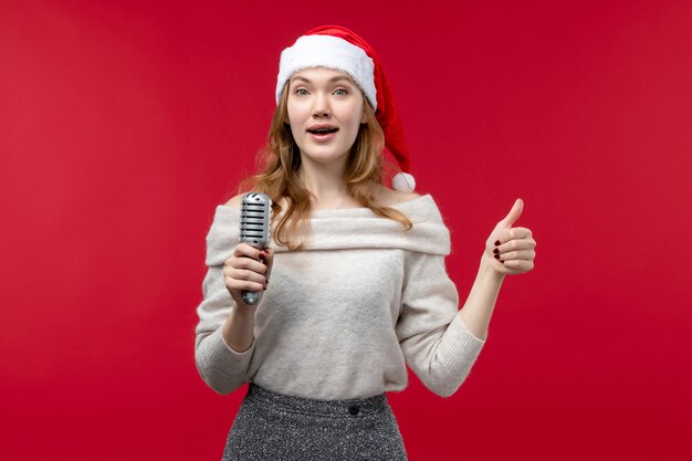 Widok z przodu ładnej kobiety trzymającej mikrofon na jasnoczerwonym