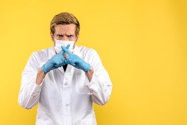Widok z przodu lekarz mężczyzna trzymający palce na żółtym tle pandemia COVID-wirus zdrowia