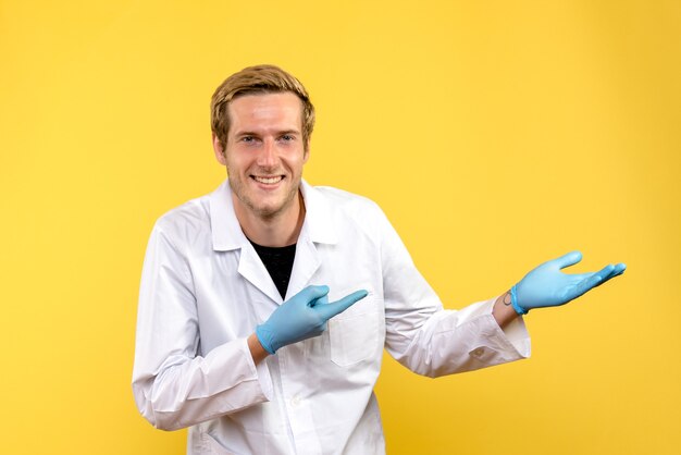 Widok z przodu lekarz mężczyzna uśmiecha się na żółtym tle pandemii medycznej covid człowieka