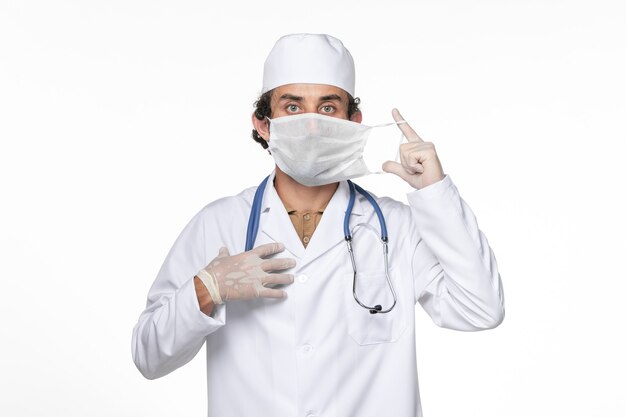 Widok z przodu lekarz mężczyzna w kombinezonie medycznym w masce na białej ścianie medycyny pandemicznej wirusa koronawirusa