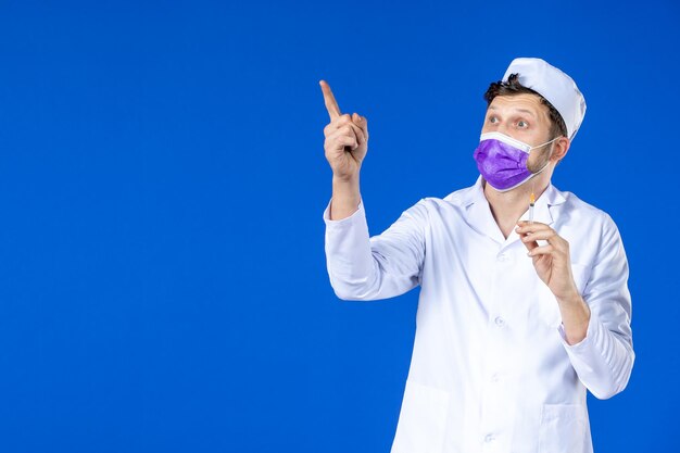 Widok z przodu lekarza płci męskiej w garniturze i fioletowej masce gospodarstwa zastrzyk na niebiesko