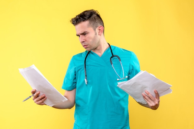 Widok z przodu lekarza płci męskiej z dokumentami na żółtej ścianie