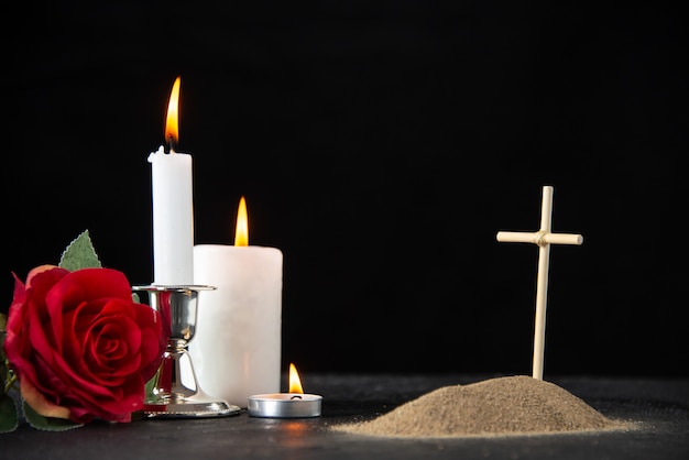 Widok z przodu małego grobu z czerwoną różą i świecami na czarno