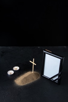 Widok z przodu małego grobu z krzyżem i ramką na obraz w ciemności