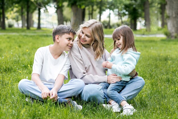 Widok z przodu mama i dzieci siedzi na trawie