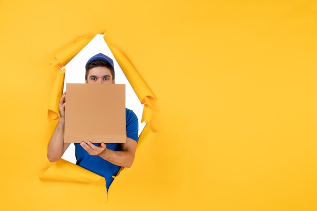 Widok z przodu męski kurier trzymający pudełko po pizzy na żółtej przestrzeni
