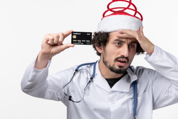 Widok z przodu męskiego lekarza trzymającego kartę bankową na białej ścianie