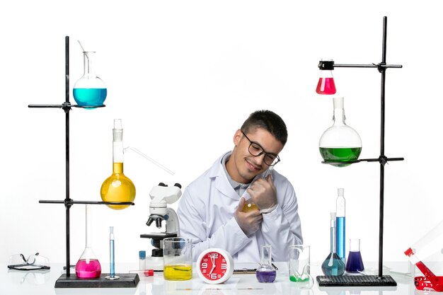 Widok z przodu mężczyzna chemik w białym garniturze medycznym, trzymając roztwór na białym tle pandemia wirusów nauki covid lab