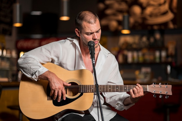 Bezpłatne zdjęcie widok z przodu mężczyzna gra na gitarze w barze