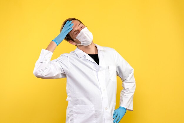 Widok z przodu mężczyzna lekarz mający ból głowy na żółtym tle pandemia wirusa COVID zdrowia