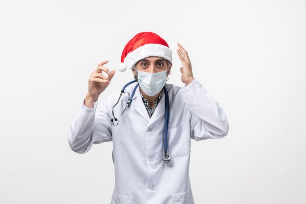 Widok z przodu mężczyzna lekarz ubrany w czerwoną czapkę na białej ścianie wirus noworocznej pandemii