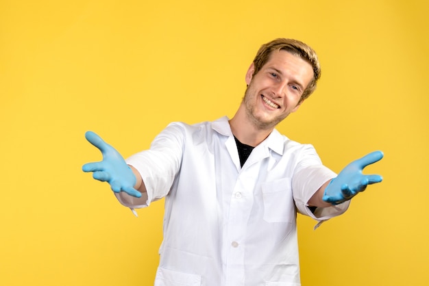Widok z przodu mężczyzna lekarz uśmiechnięty na żółtym tle covid-human medic emocje