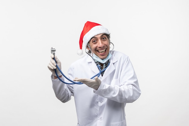 Widok Z Przodu Mężczyzna Lekarz Uśmiechnięty Trzymając Stetoskop Na Białej ścianie Emocja Covid-virus