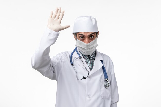 Widok z przodu mężczyzna lekarz w białym kombinezonie medycznym w masce z powodu wirusa choroby białej podłogi - pandemia szpitala