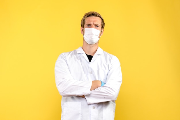 Widok z przodu mężczyzna lekarz w masce na żółtym tle pandemia zdrowia COVID-MED