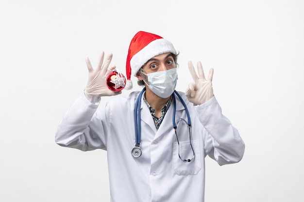 Widok z przodu mężczyzna lekarz w masce z zabawką na białym biurku wirus zdrowia covid nowy rok