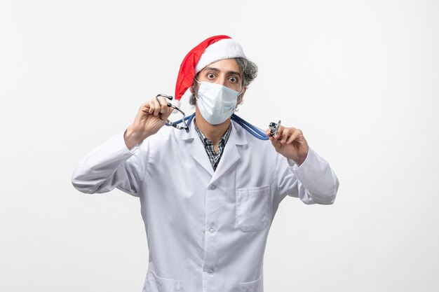 Widok z przodu mężczyzna lekarz w sterylnej masce na białym biurku covid virus wakacje nowy rok