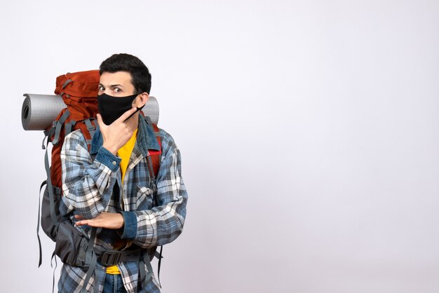 Widok z przodu mężczyzna podróżnik z plecakiem i maską, kładąc rękę na brodzie