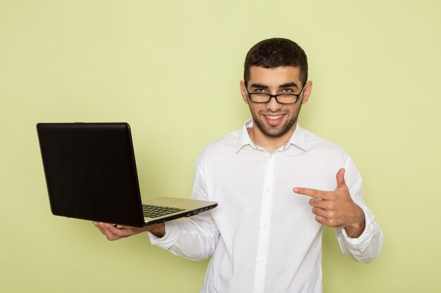 Widok Z Przodu Mężczyzna Pracownik Biurowy W Białej Koszuli Trzymając Laptopa Uśmiechając Się Na Jasnozielonej ścianie
