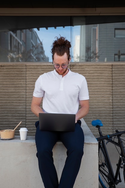 Widok z przodu mężczyzna pracujący na laptopie na zewnątrz