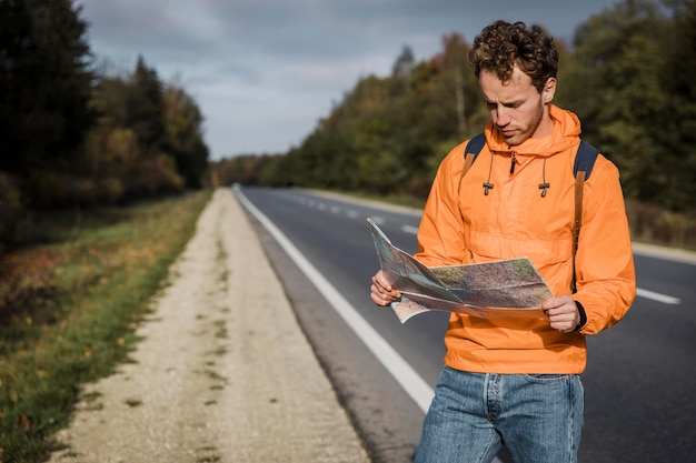 Bezpłatne zdjęcie widok z przodu mężczyzny trzymającego mapę i siedzącego wzdłuż drogi