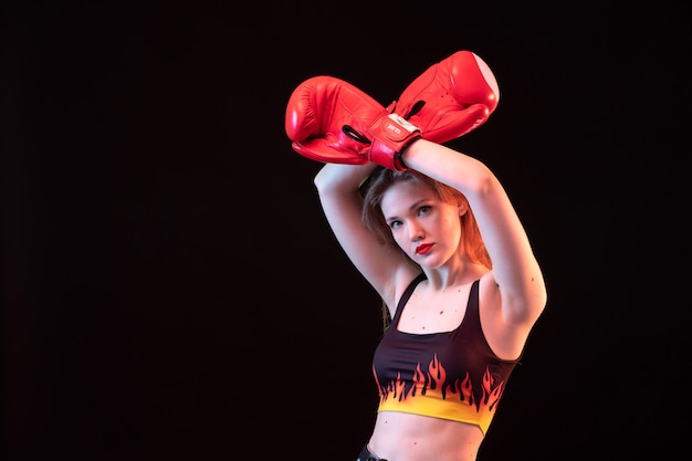 Widok z przodu młoda atrakcyjna dama w czerwonych rękawicach bokserskich ogień koszuli na czarnym tle sport boks szkolenia