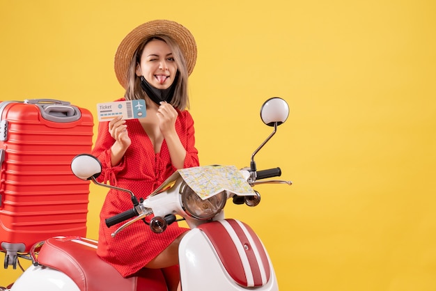 Widok z przodu młoda dama na motorowerze z czerwoną walizką wystającą z języka trzymającego bilet
