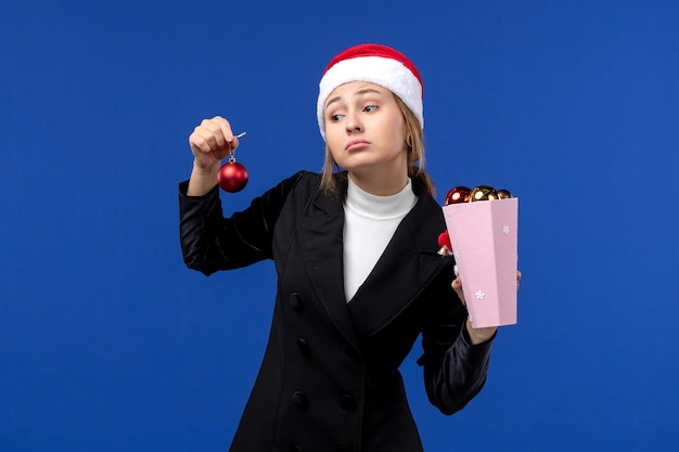 Bezpłatne zdjęcie widok z przodu młoda dama trzyma zabawki drzewne na niebieskiej ścianie emocje nowy rok wakacje niebieski