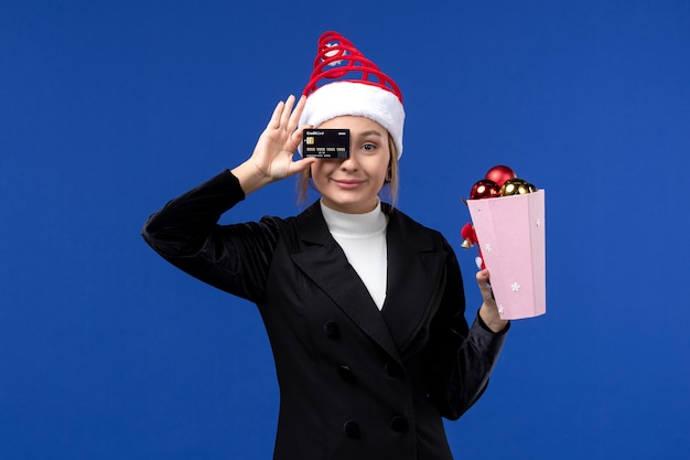 Bezpłatne zdjęcie widok z przodu młoda dama z zabawkami drzewnymi i kartą bankową na niebieskiej ścianie emocje nowy rok wakacje