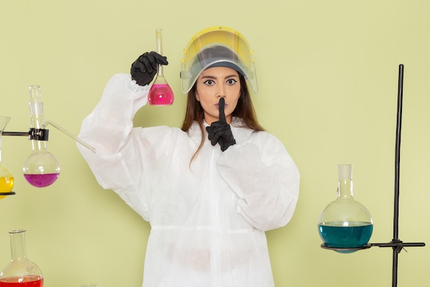 Bezpłatne zdjęcie widok z przodu młoda kobieta chemik w specjalnym kombinezonie ochronnym pracująca z roztworami na zielonej ścianie praca chemiczna chemia kobiet laboratorium naukowe