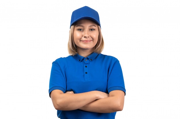 Widok z przodu młoda kobieta kurier w niebieskim mundurze, pozująca z uśmiechem na twarzy