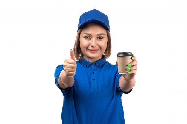 Widok z przodu młoda kobieta kurier w niebieskim mundurze trzymając filiżankę kawy