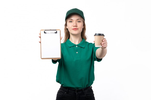 Widok z przodu młoda kobieta kurier w zielonym mundurze trzymając filiżanki kawy i notatnik na białym tle