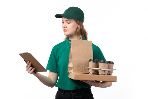 Widok z przodu młoda kobieta kurier w zielonym mundurze, trzymając filiżanki kawy opakowania żywności i notatnik na białym tle
