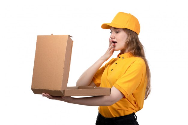 Widok z przodu młoda kobieta kurier żeński pracownik usług dostawy żywności uśmiecha się trzymając puste pudełko po pizzy, otwierając go z zaskoczonym wyrazem na białym tle