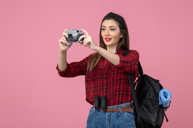 Widok z przodu młoda kobieta robienie zdjęć aparatem na różowym tle kolor zdjęcia kobiety