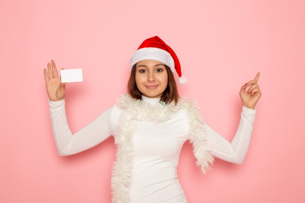 Widok z przodu młoda kobieta trzyma białą kartę bankową na różowej ścianie Boże Narodzenie nowy rok moda kolor pieniądze wakacje
