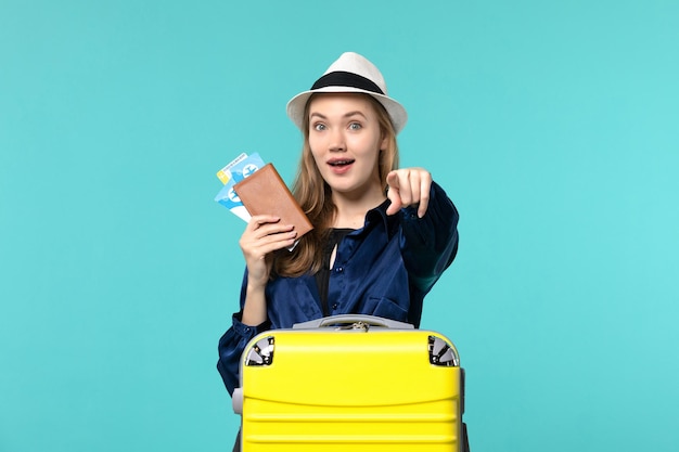 Widok z przodu młoda kobieta trzyma bilety i przygotowuje się do podróży na niebieskim tle podróż morze wakacje podróż samolotem