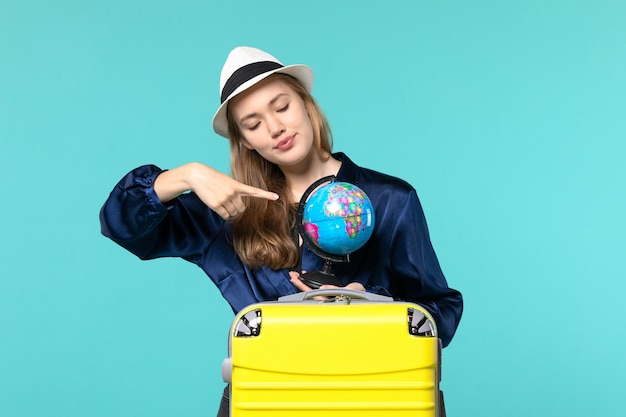 Bezpłatne zdjęcie widok z przodu młoda kobieta trzyma kulę ziemską i przygotowuje się do wakacji na płaszczyźnie niebieskim tle samica wakacje podróż podróż morze