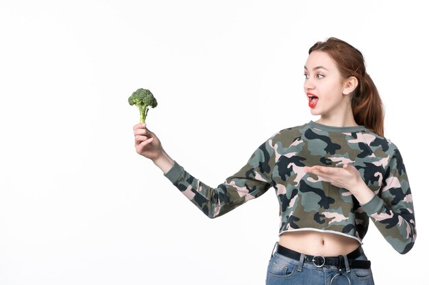 Widok z przodu młoda kobieta trzyma małe zielone brokuły na białym tle sałatka obiad posiłek dieta zdrowie danie ciało poziome