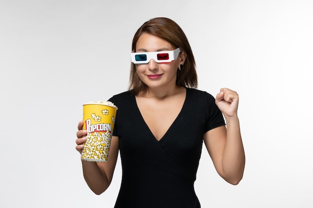 Bezpłatne zdjęcie widok z przodu młoda kobieta trzyma pakiet popcornu d okulary i uśmiecha się na białej powierzchni